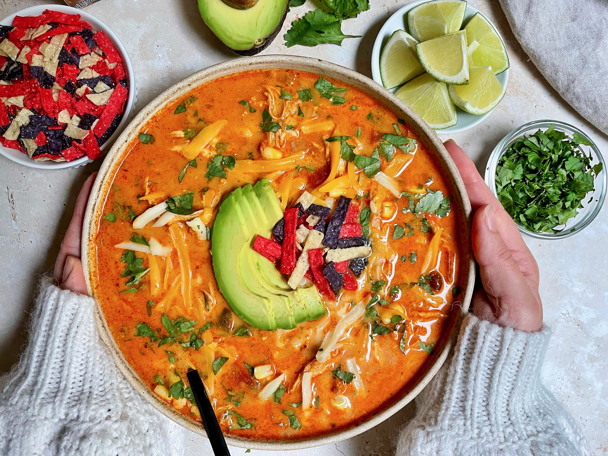 Two hands holding a bowl of chicken enchilada soup.