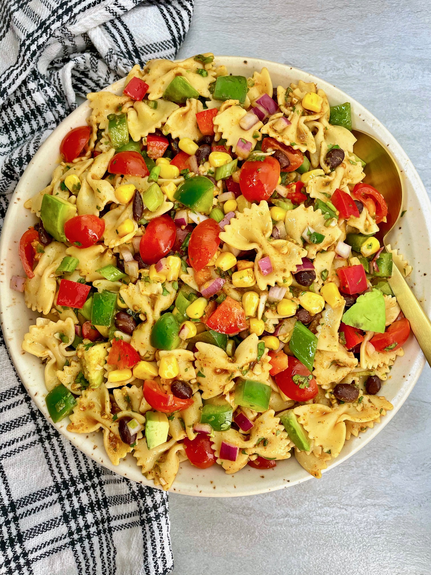a large bowl of southwest pasta salad with a serving spoon