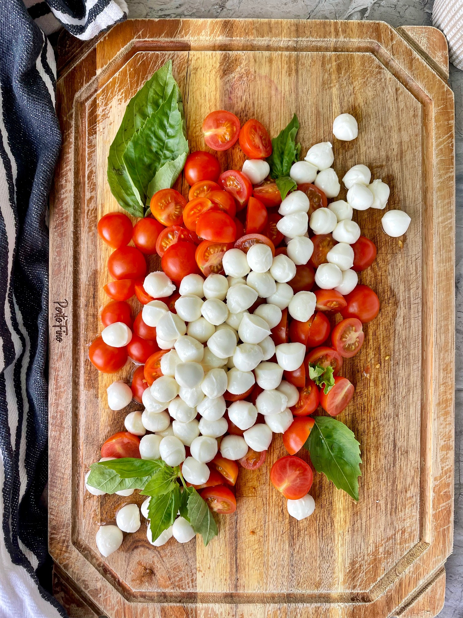a cutting board with cherry tomatoes, mozzarella balls and basil