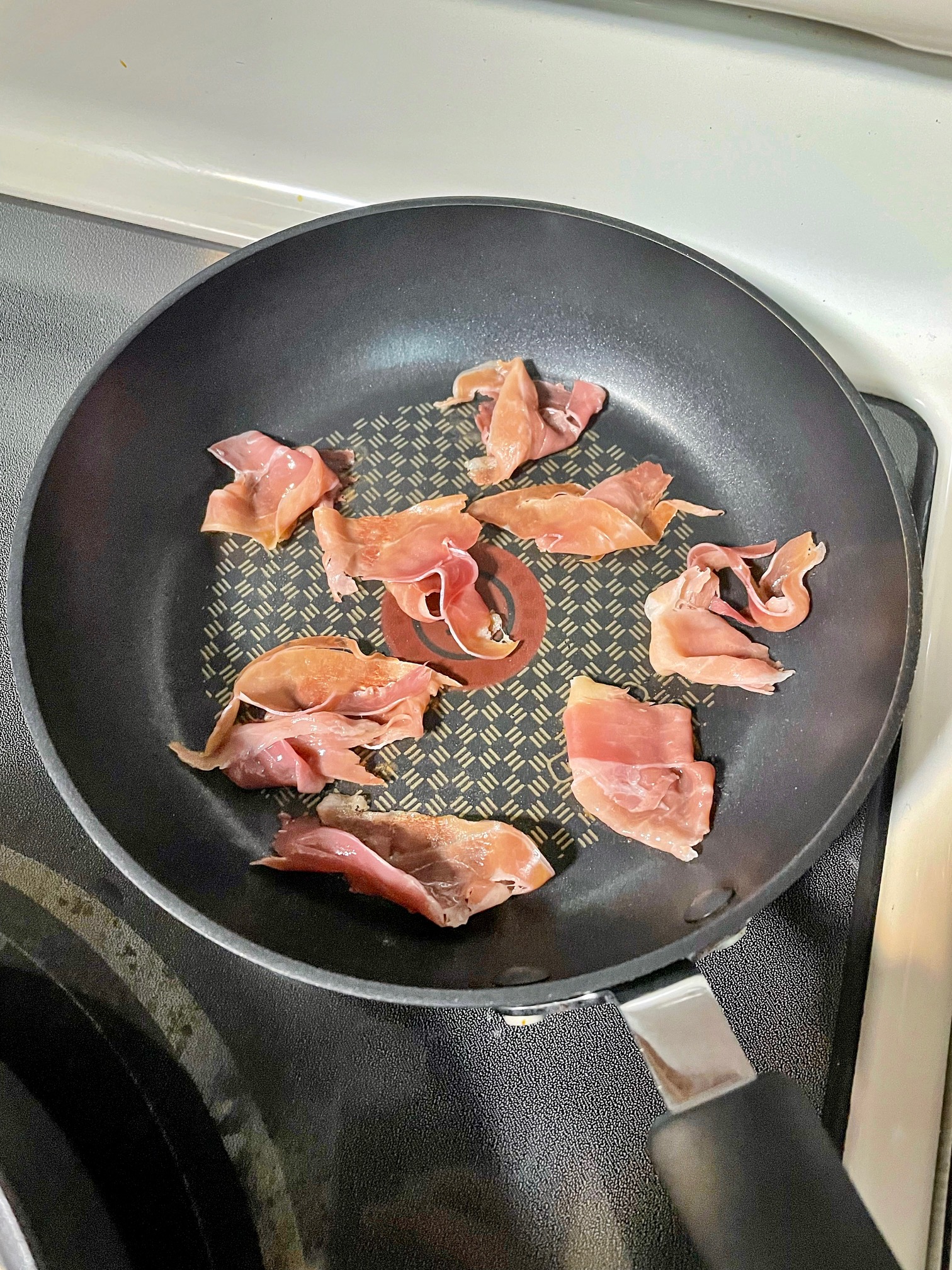 pieces of prosciutto crisping in a pan