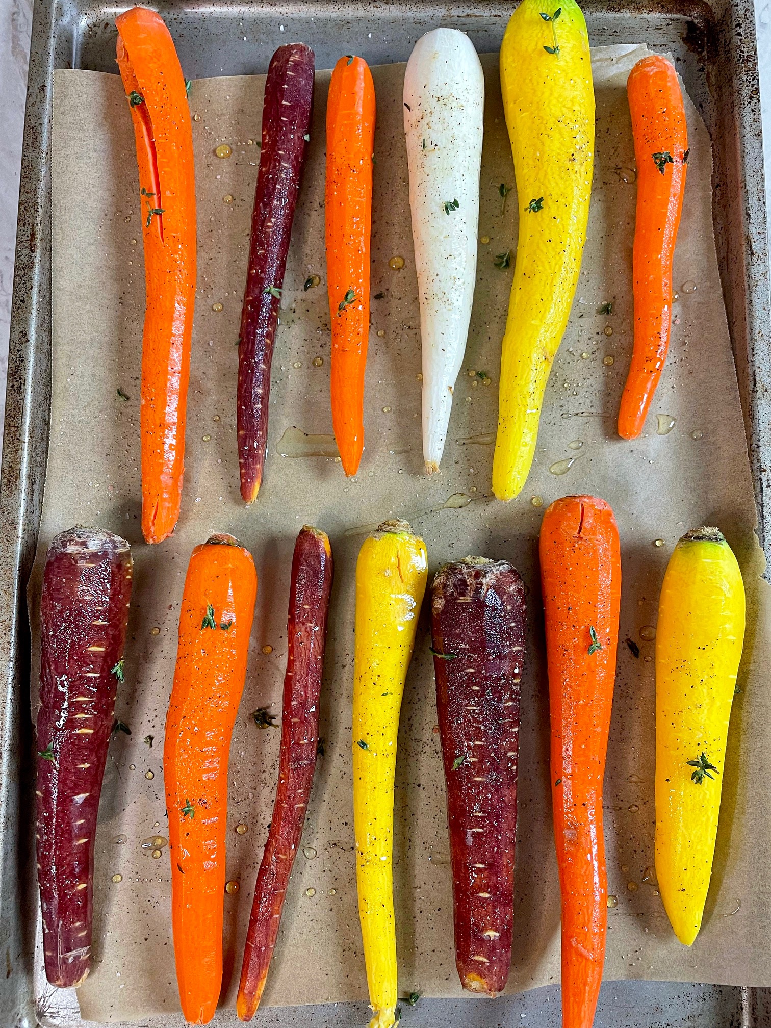 multi color carrots on a baking sheet ready for roasting