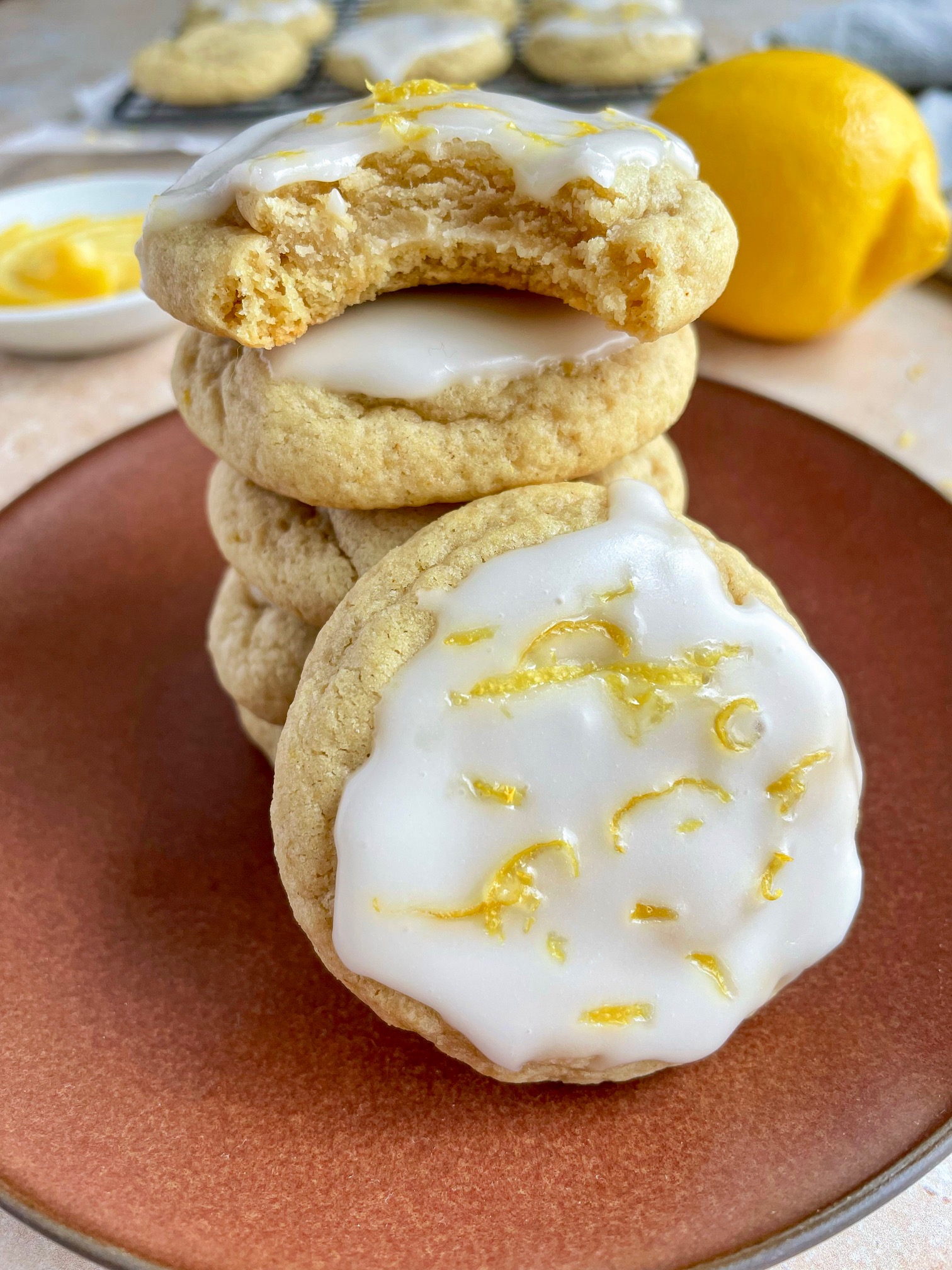 a stack of lemon cookies with a bite taken out of the top cookie to show the inside texture.