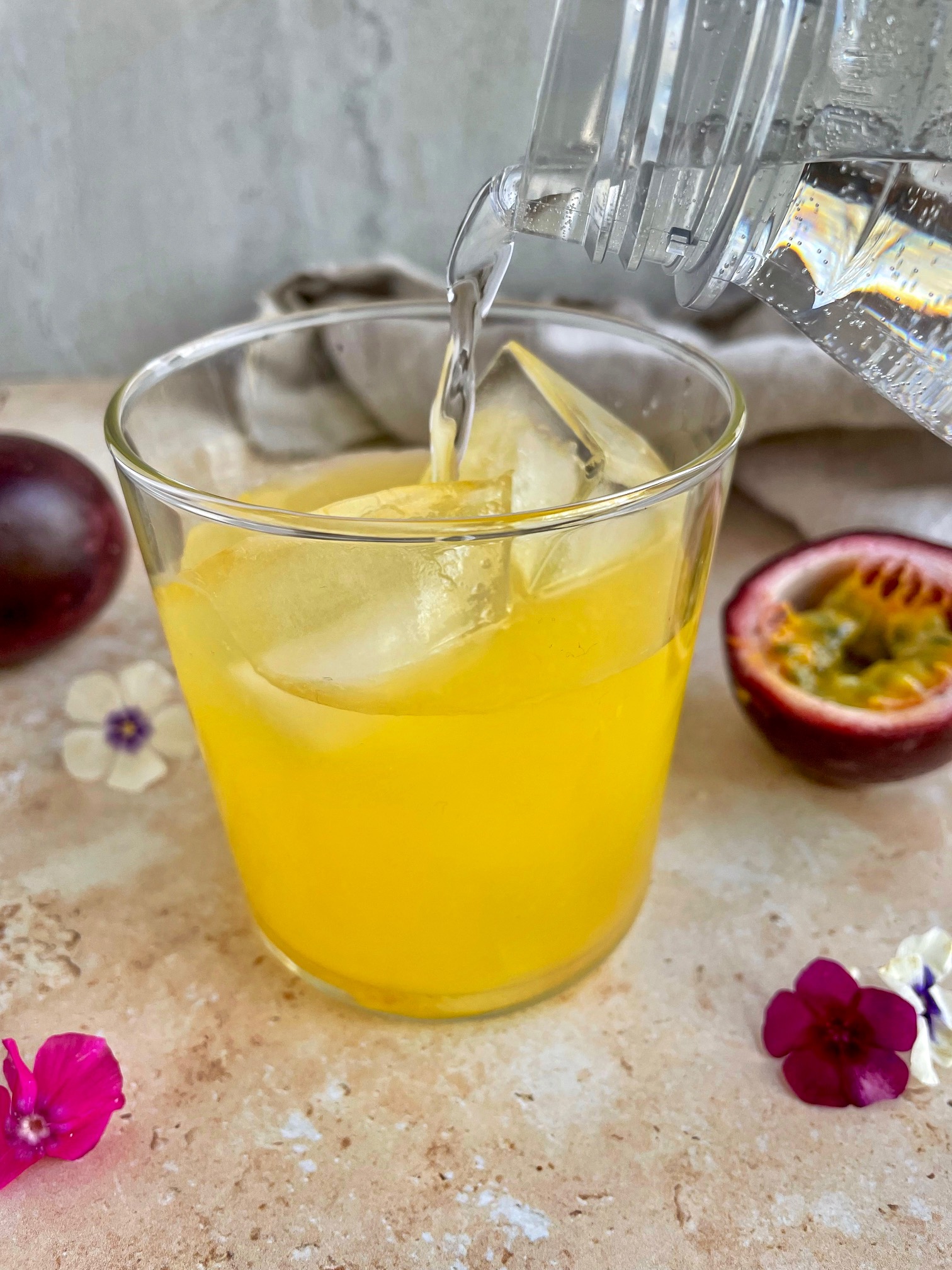 topping off the passion fruit cocktail with seltzer.