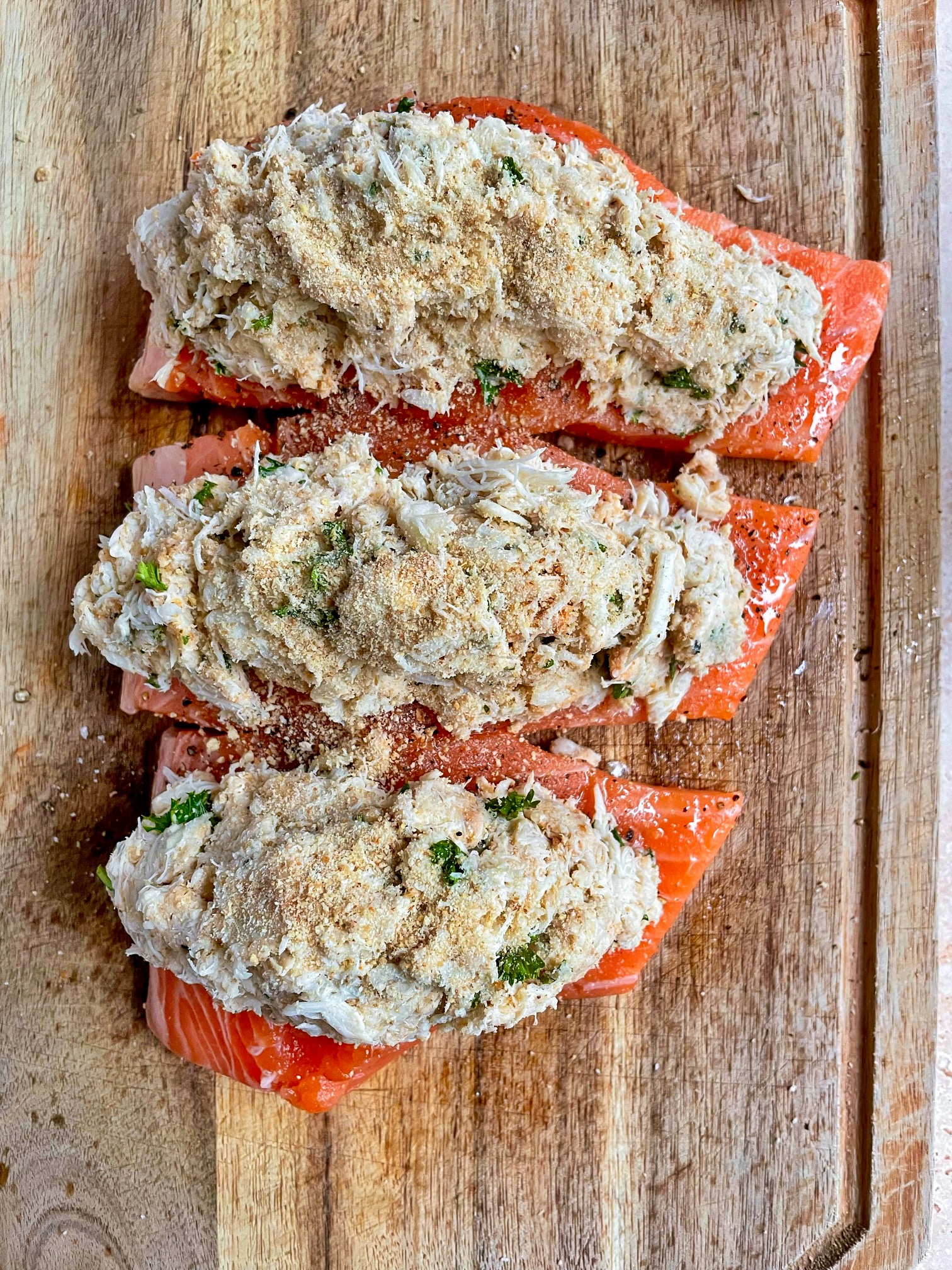 three salmon fillets stuffed with crab filling on a cutting board before air frying.