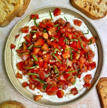 a bowl of whipped ricotta bruschetta dip with crostinis around the bowl.