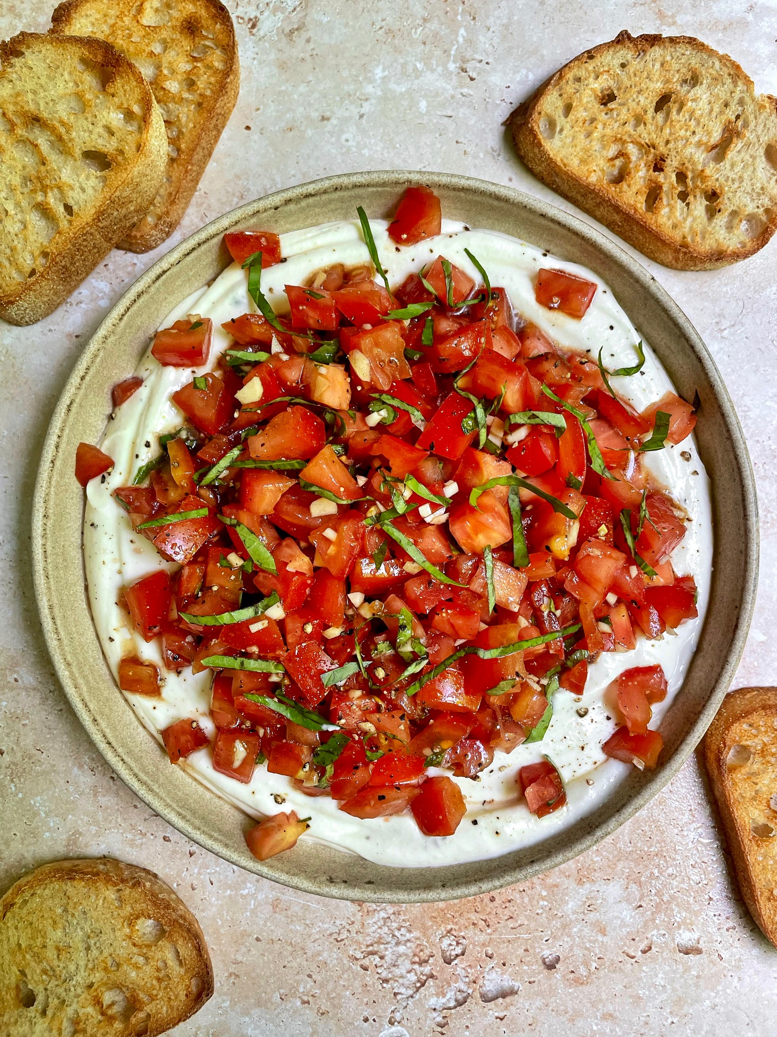 a bowl of whipped ricotta bruschetta dip with crostinis around the bowl.