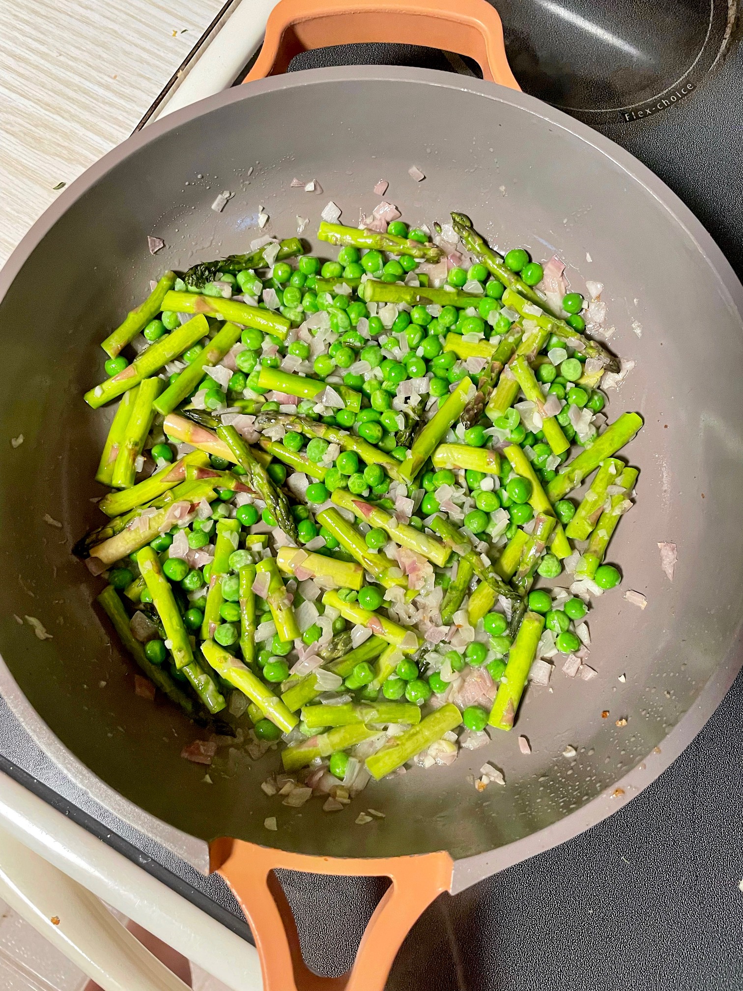 sauteed garlic, shallots, peas and asparagus in a frying pan.
