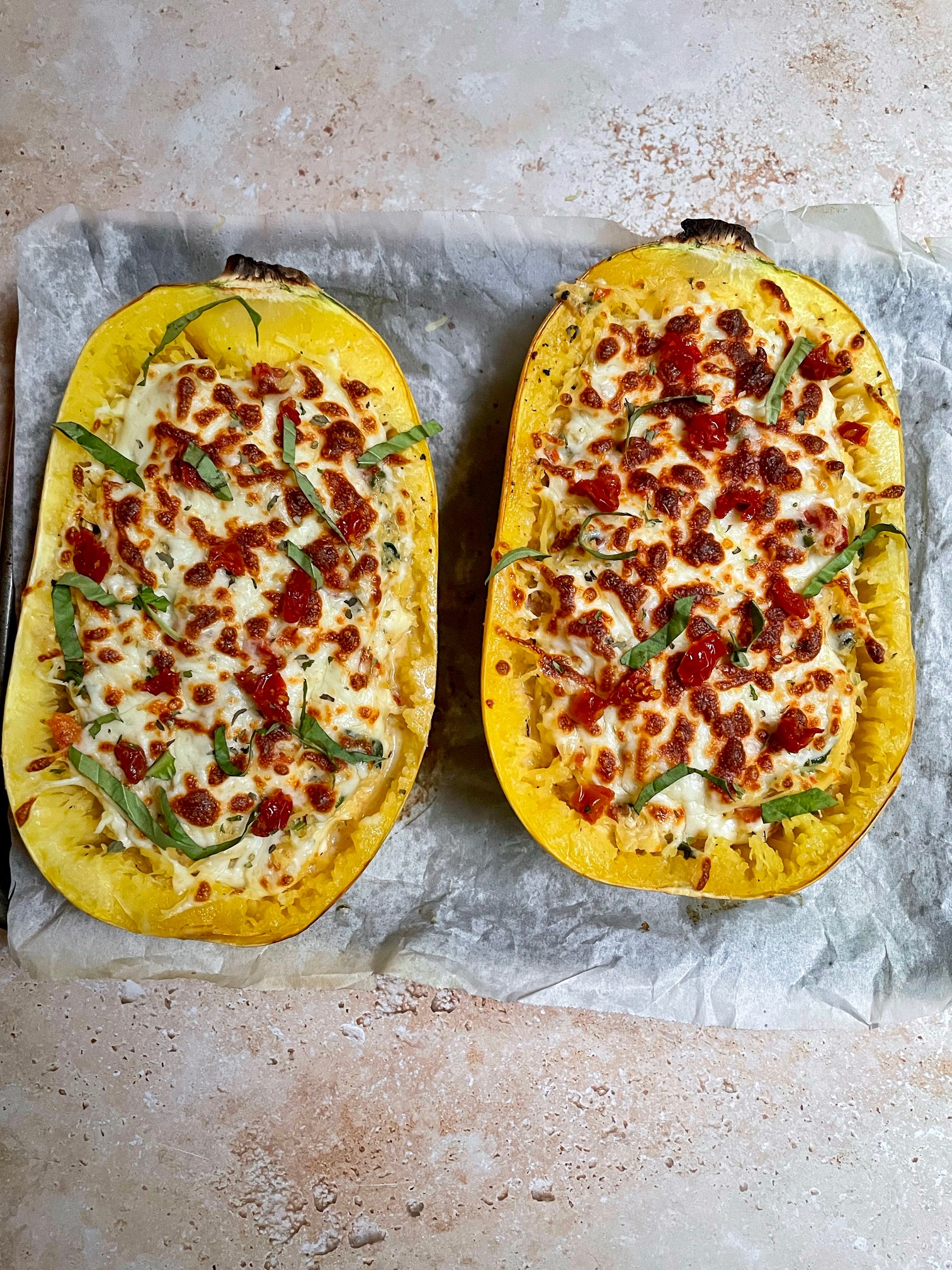 the finished tuscan spaghetti squash boats with melted and golden brown cheese on top.