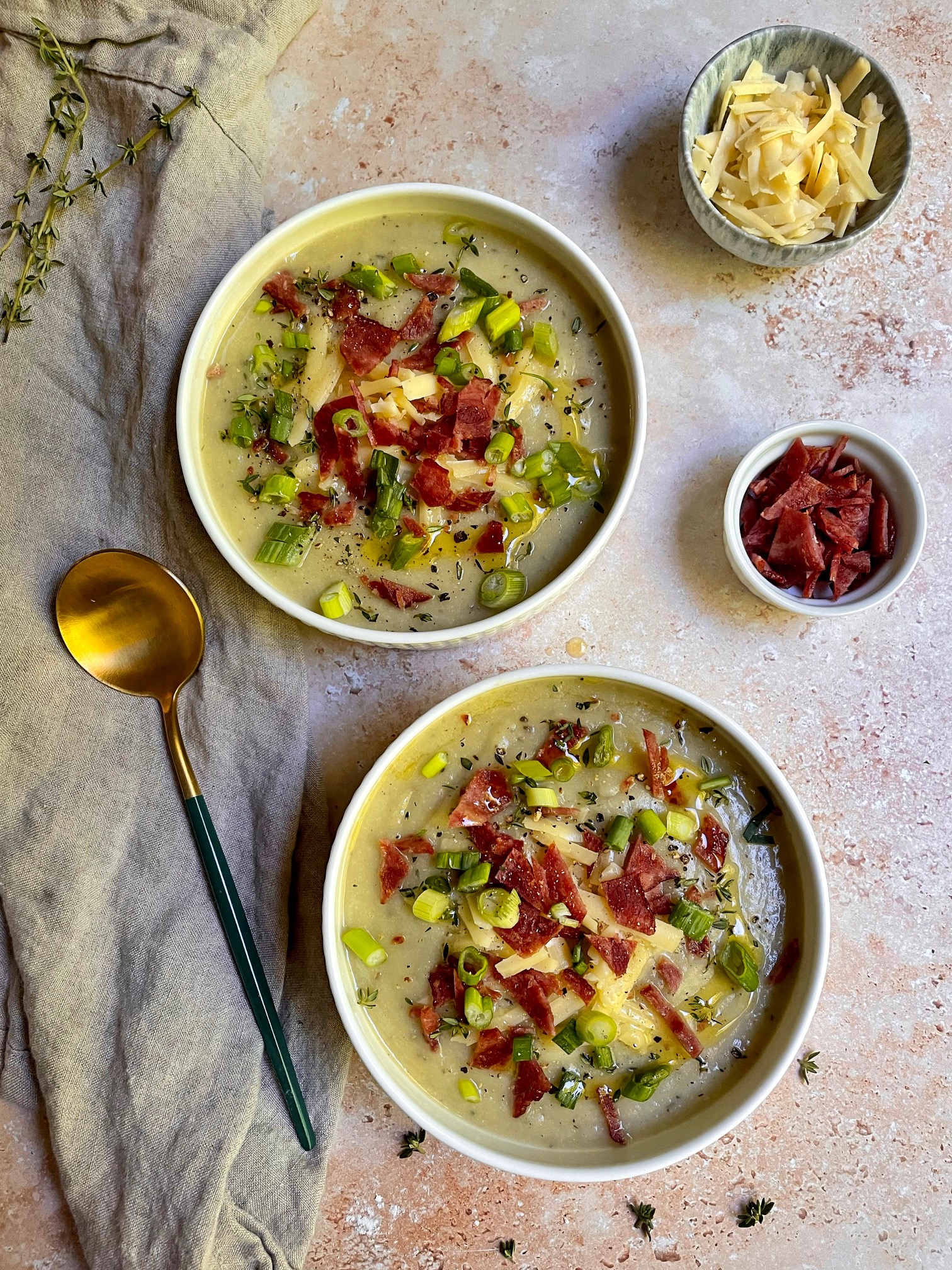 Leek, potato and cauliflower soup in two bowls with toppings.