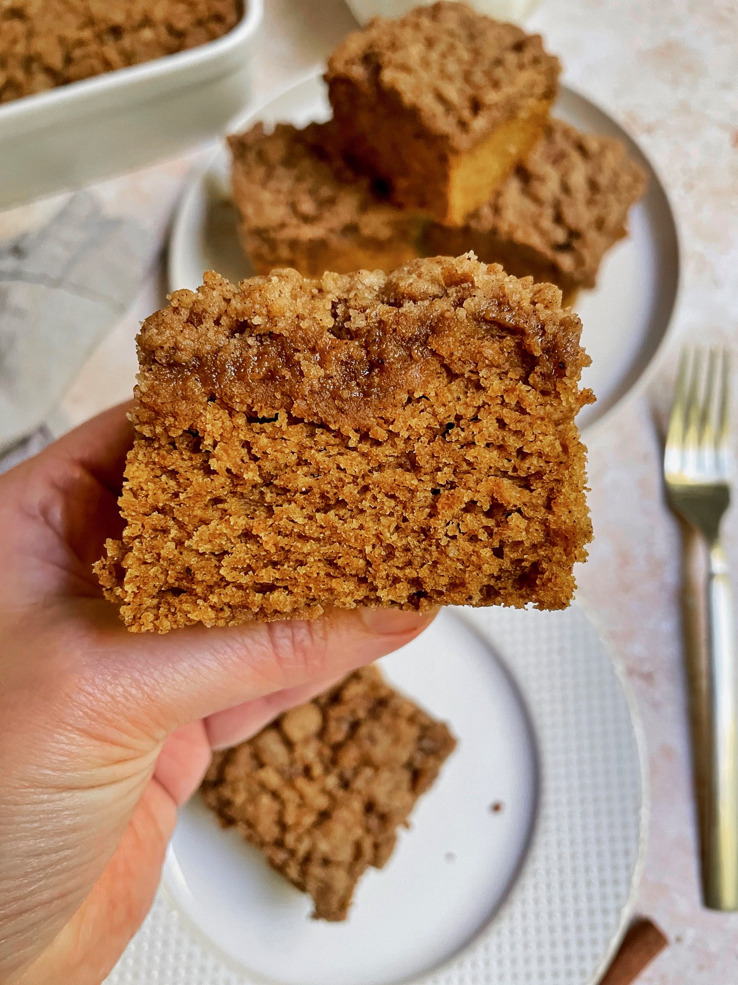 Holding up a piece of pumpkin coffee cake close to the camera to show the cake texture.