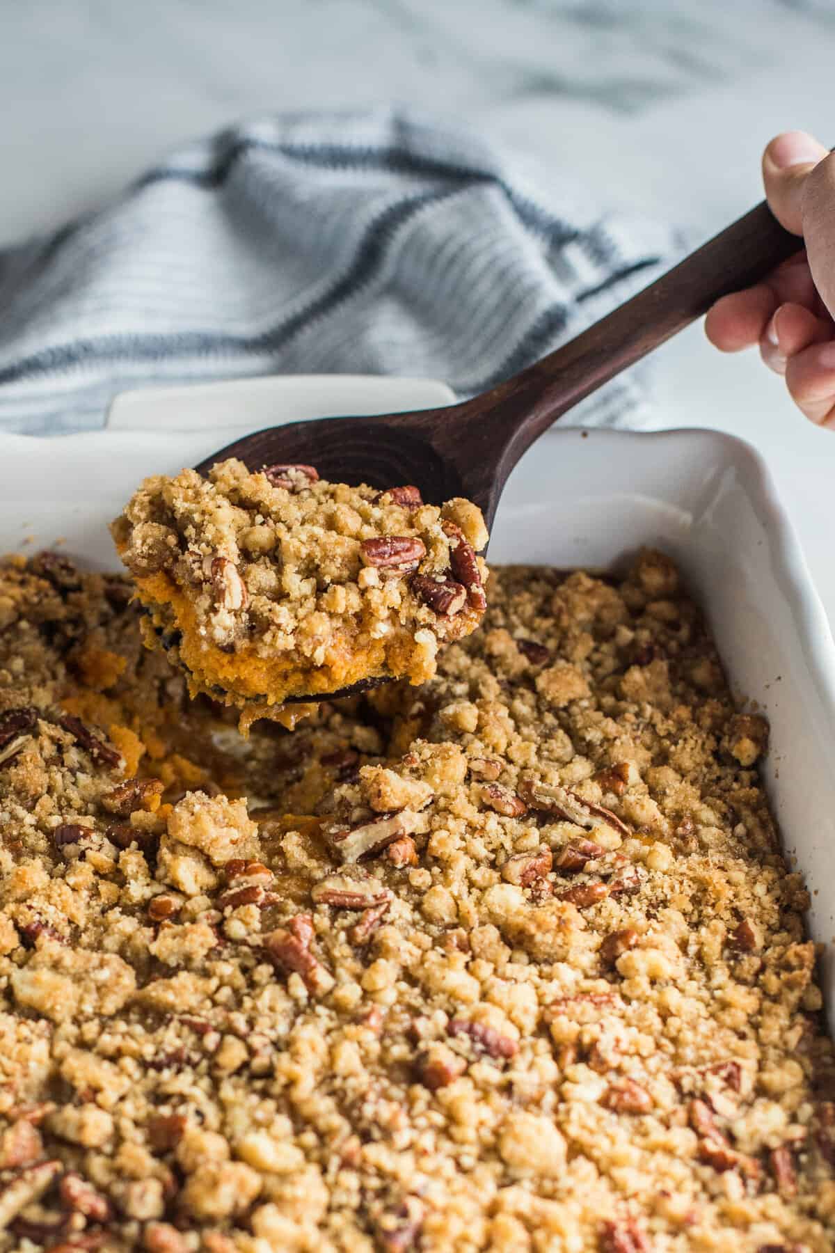 Sweet potato souffle in a baking dish with a spoon.