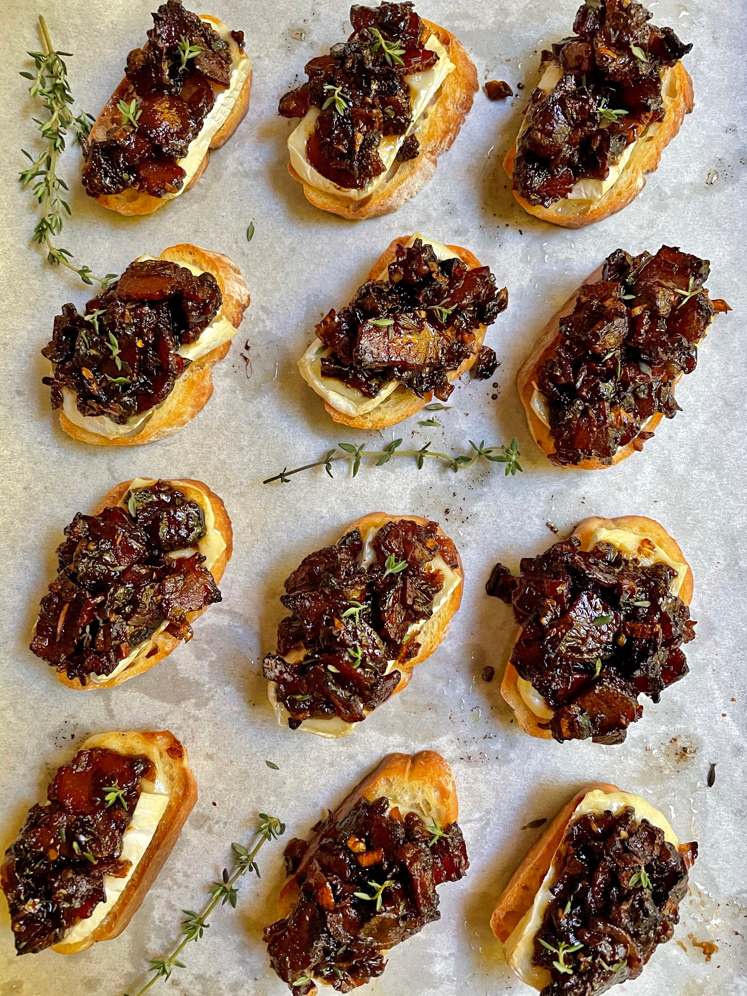 brie and bacon jam crostini on a baking sheet.