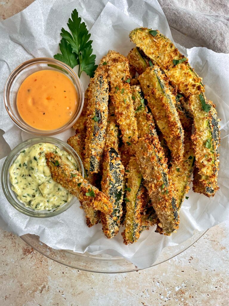 a basket of air fryer zucchini fries with two sauces for dipping.