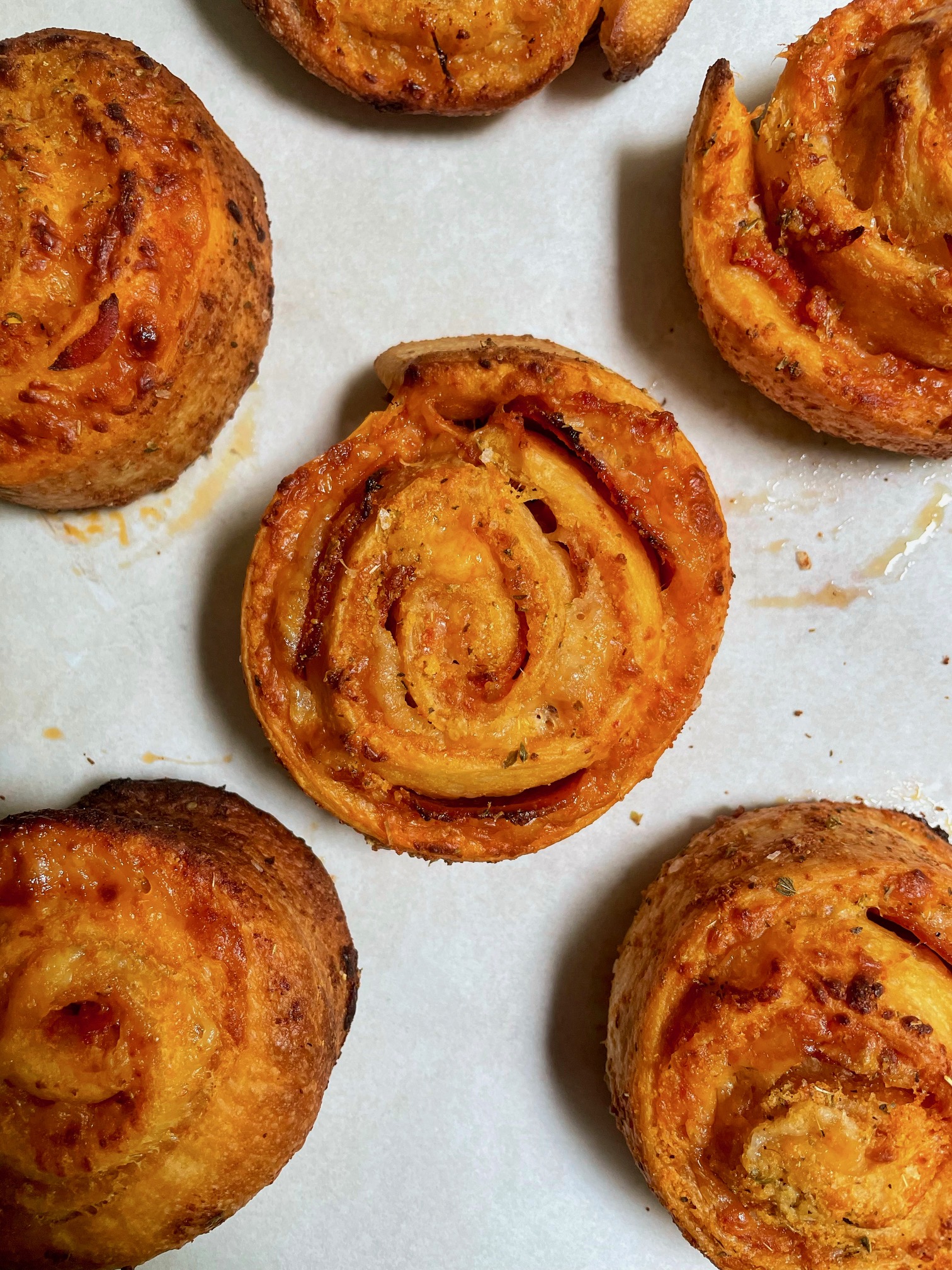 Pizza rolls cooling on parchment paper.