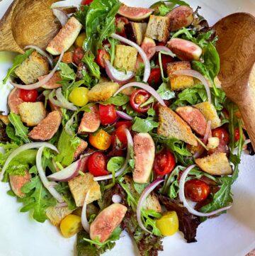 Fig Panzanella Salad in a big serving bowl with serving utensils.