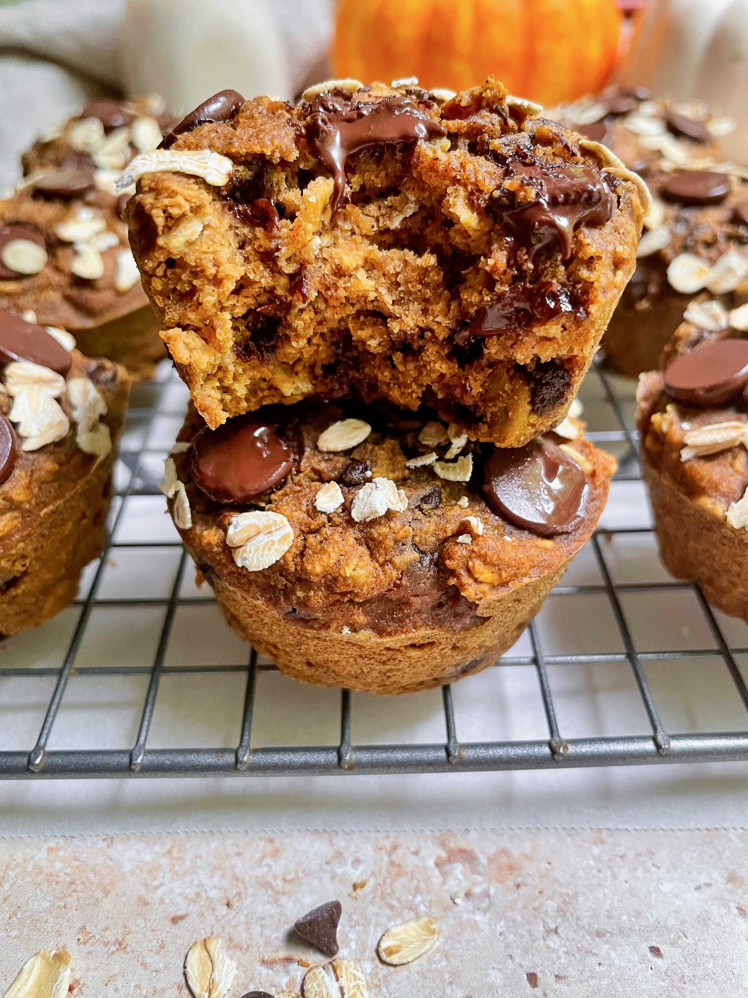 A stack of oat flour pumpkin muffins with a bite taken out of the top muffin.