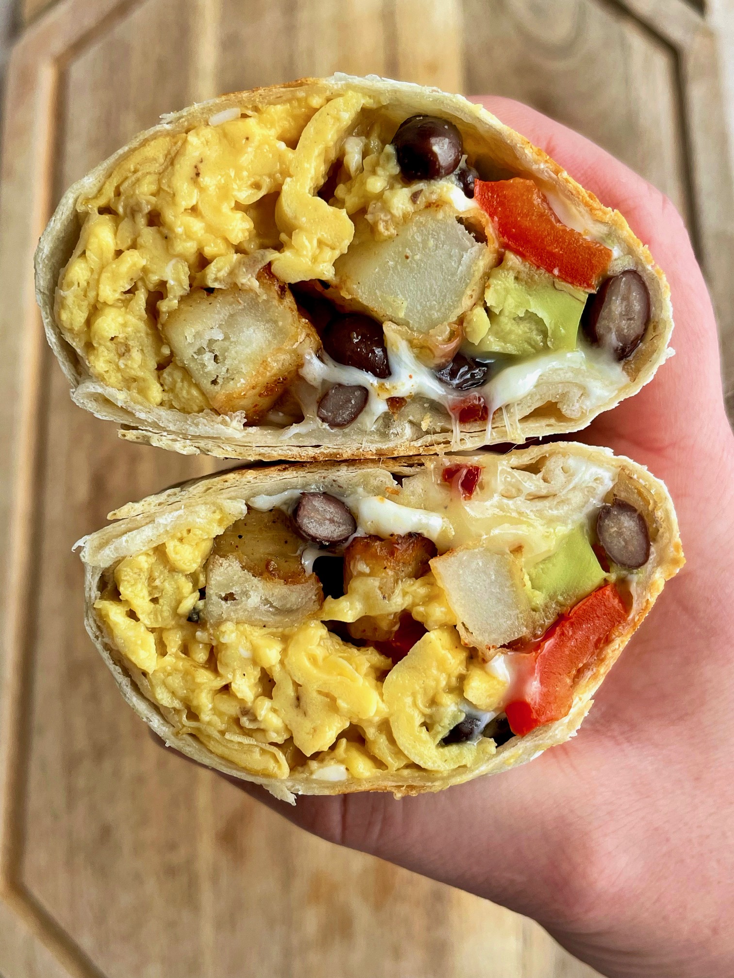 The cross section of a breakfast burrito with potaotes.