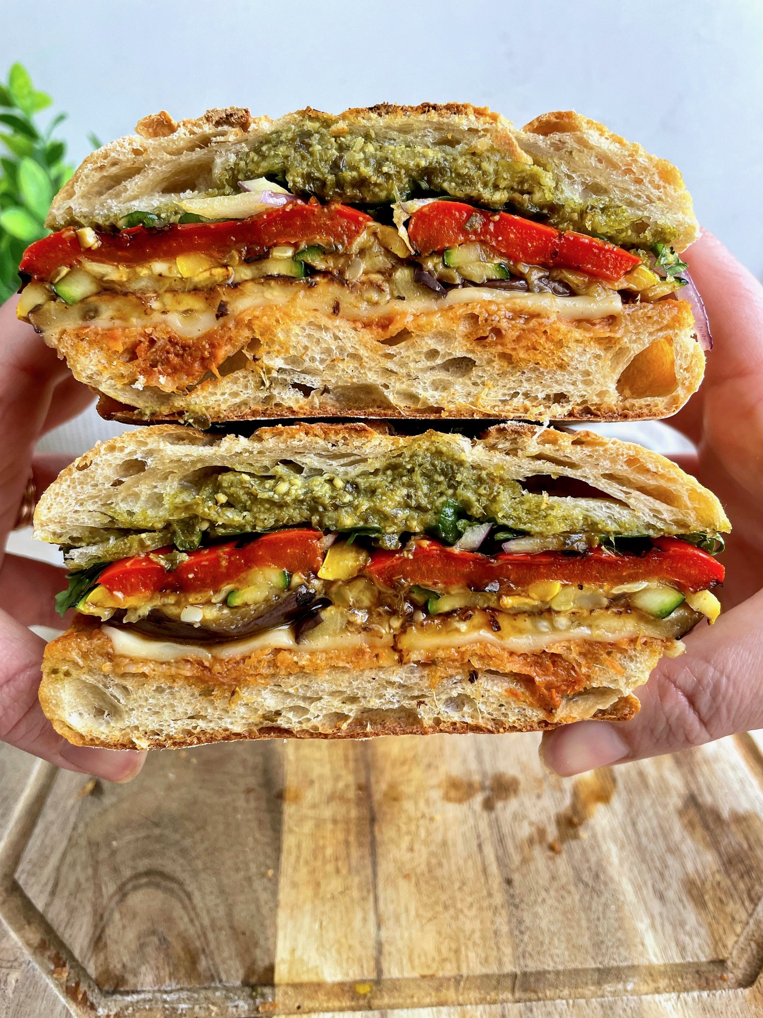 Holding two slices of grilled vegetable panini to show cross section.