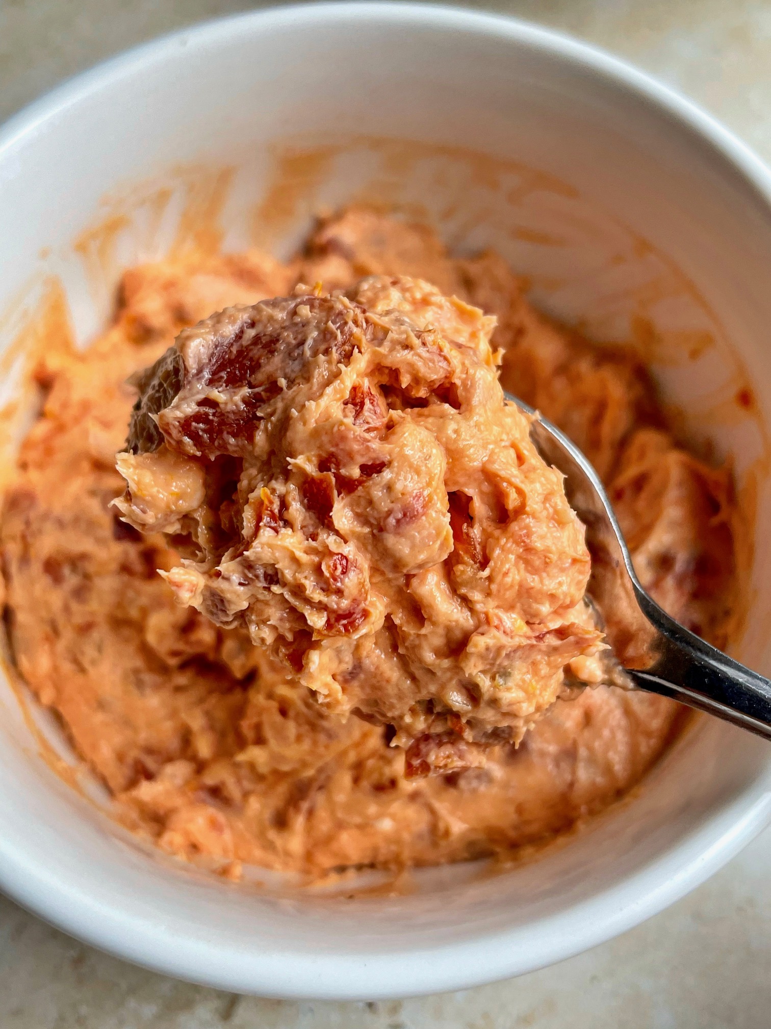 The sun-dried tomato cream cheese spread on a spoon.