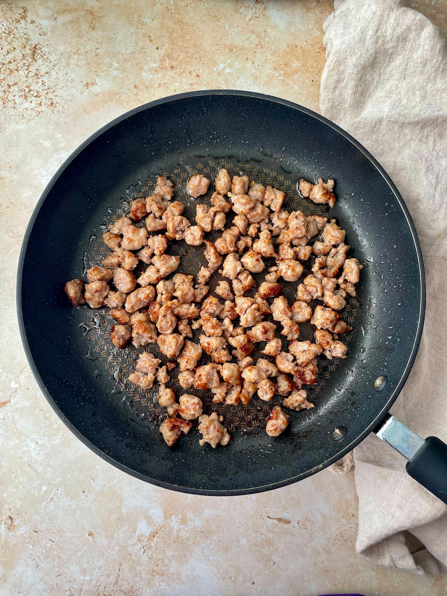 A frying pan with the cooked crumbled breakfast sausage.