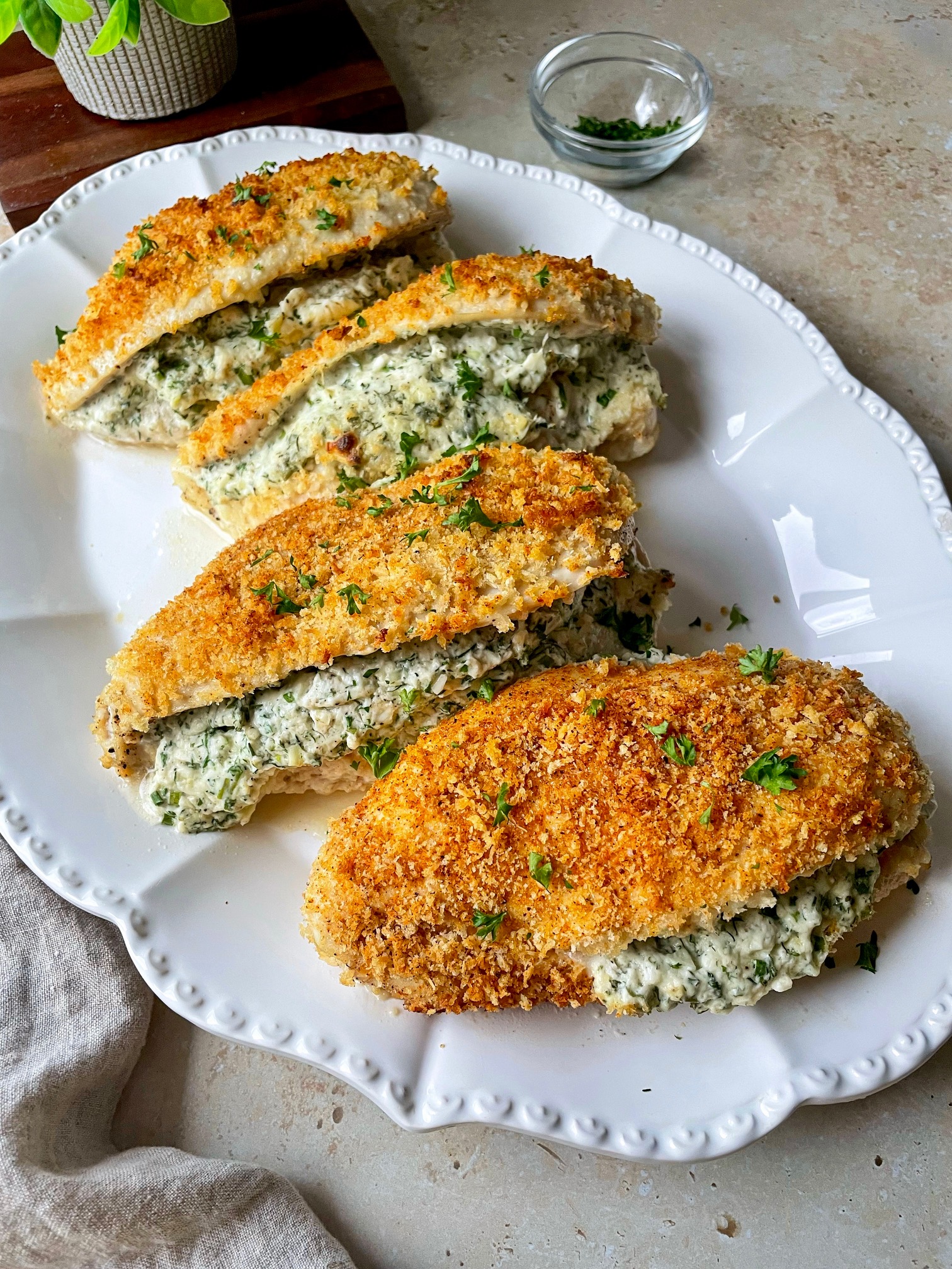 A larger platter with four garlic herb stuffed chicken at an angle so you can see the filling.