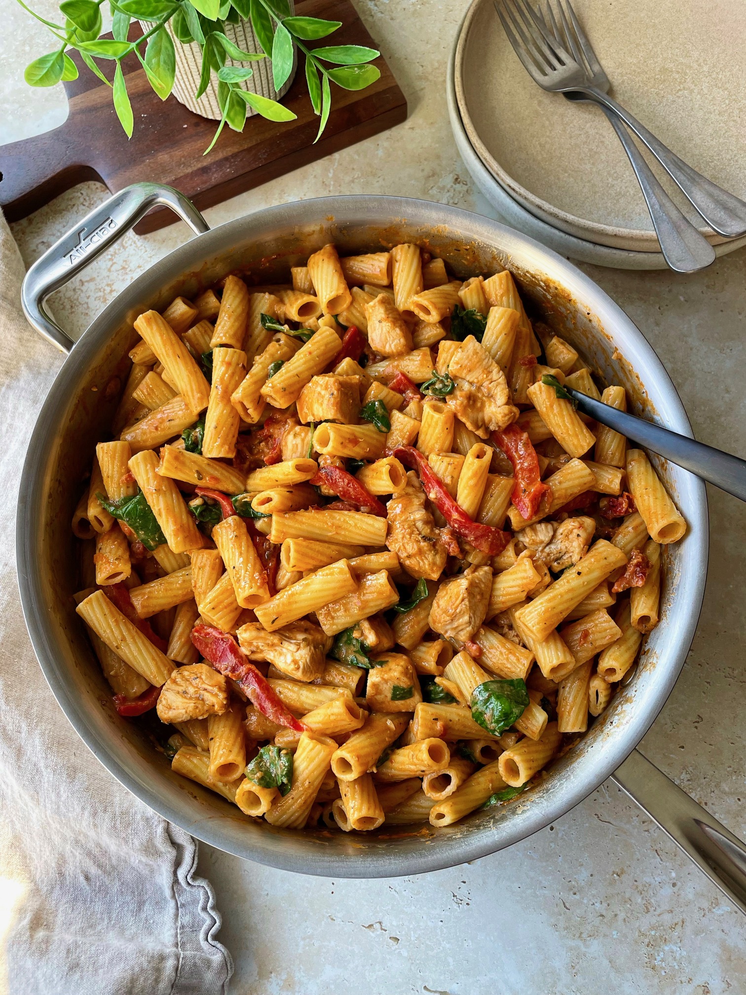 Creamy tomato pesto pasta with chicken in the pan. 