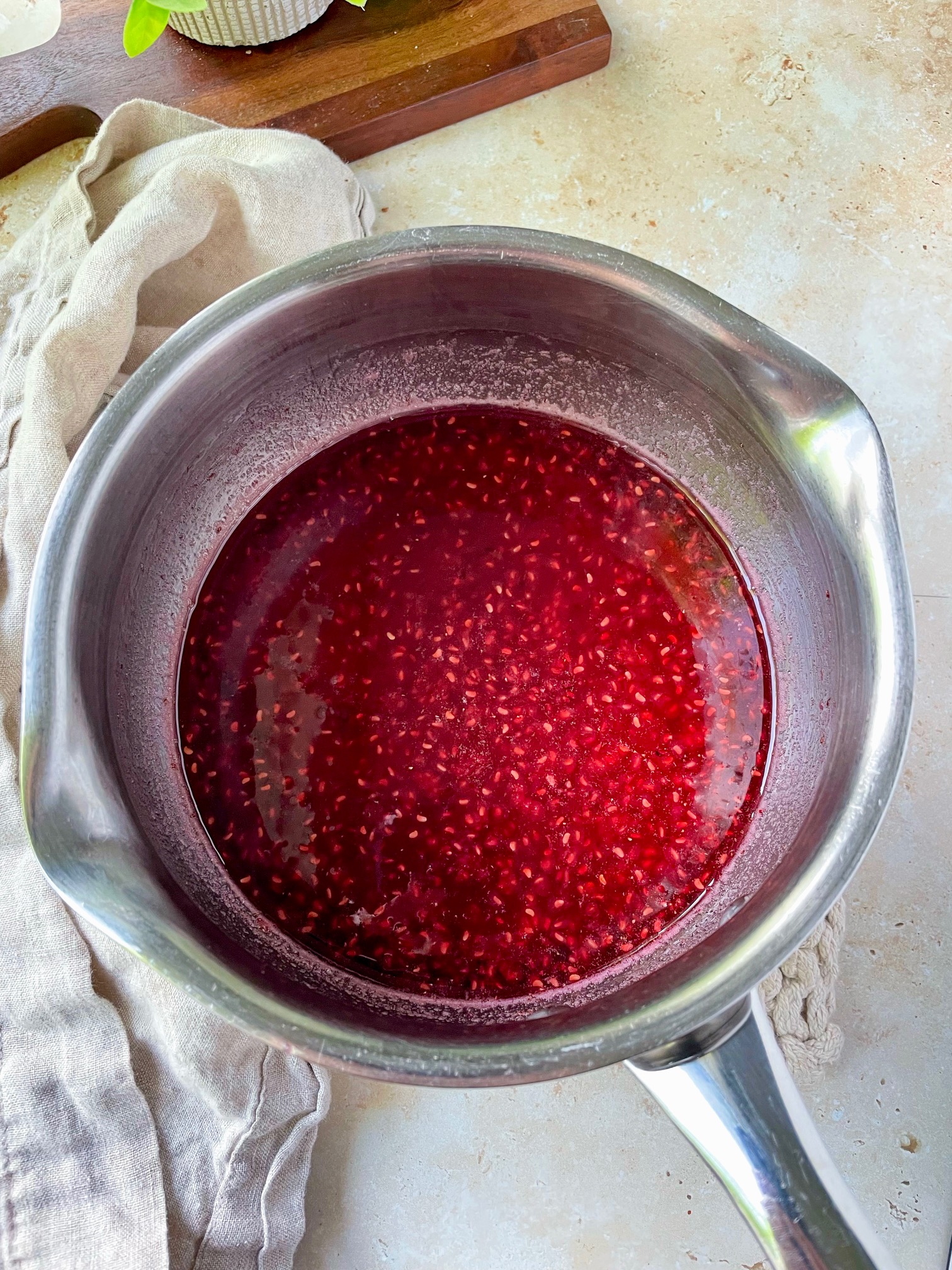 Raspberry simple syrup in a sauce pan before straining the seeds out.