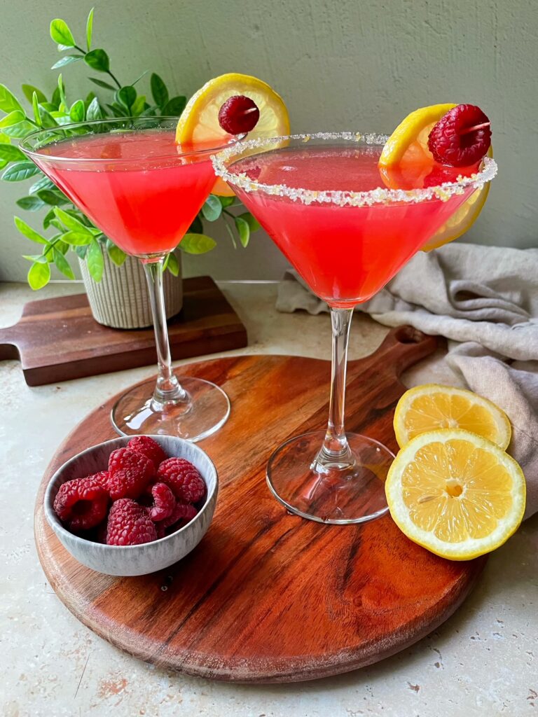 Two raspberry lemon drop martinis on a wooden board.