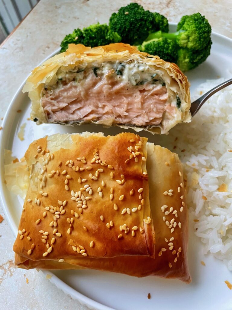 The cross section of spinach feta salmon in phyllo to show flaky top and inside layers.