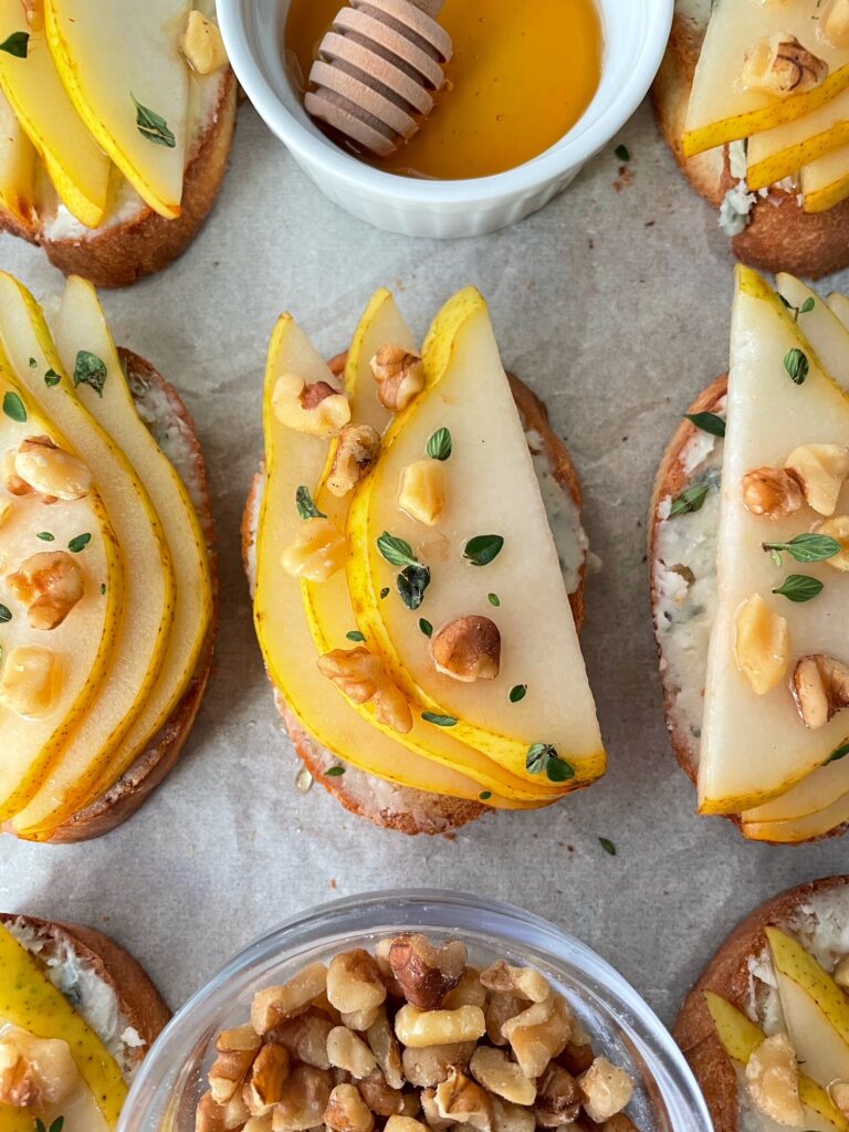 A close up of pear, blue cheese and honey crostini.