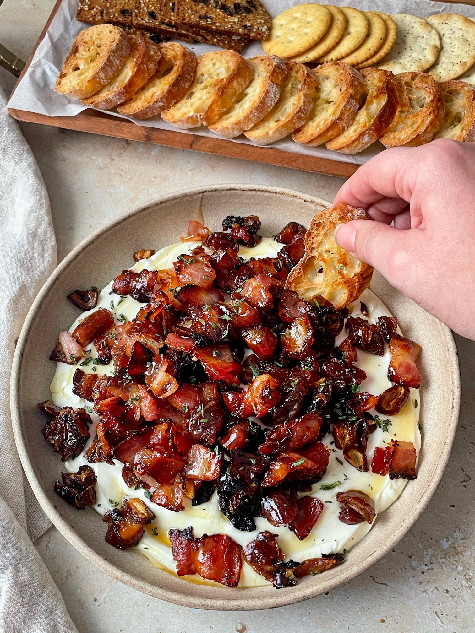 Dipping a slice of toasted baguette into bacon date whipped goat cheese dip.
