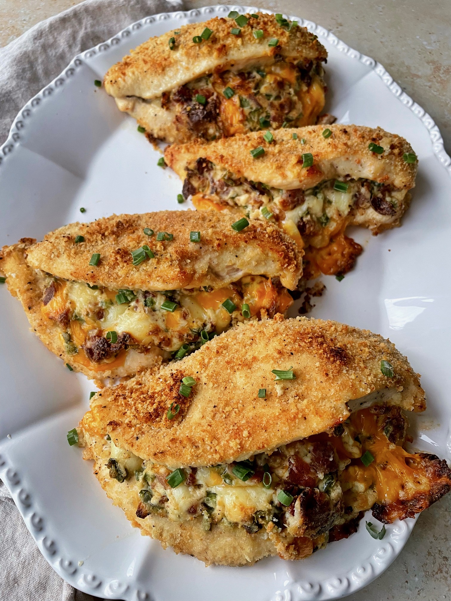 Four jalapeƱo popper stuffed chicken breasts on a platter.