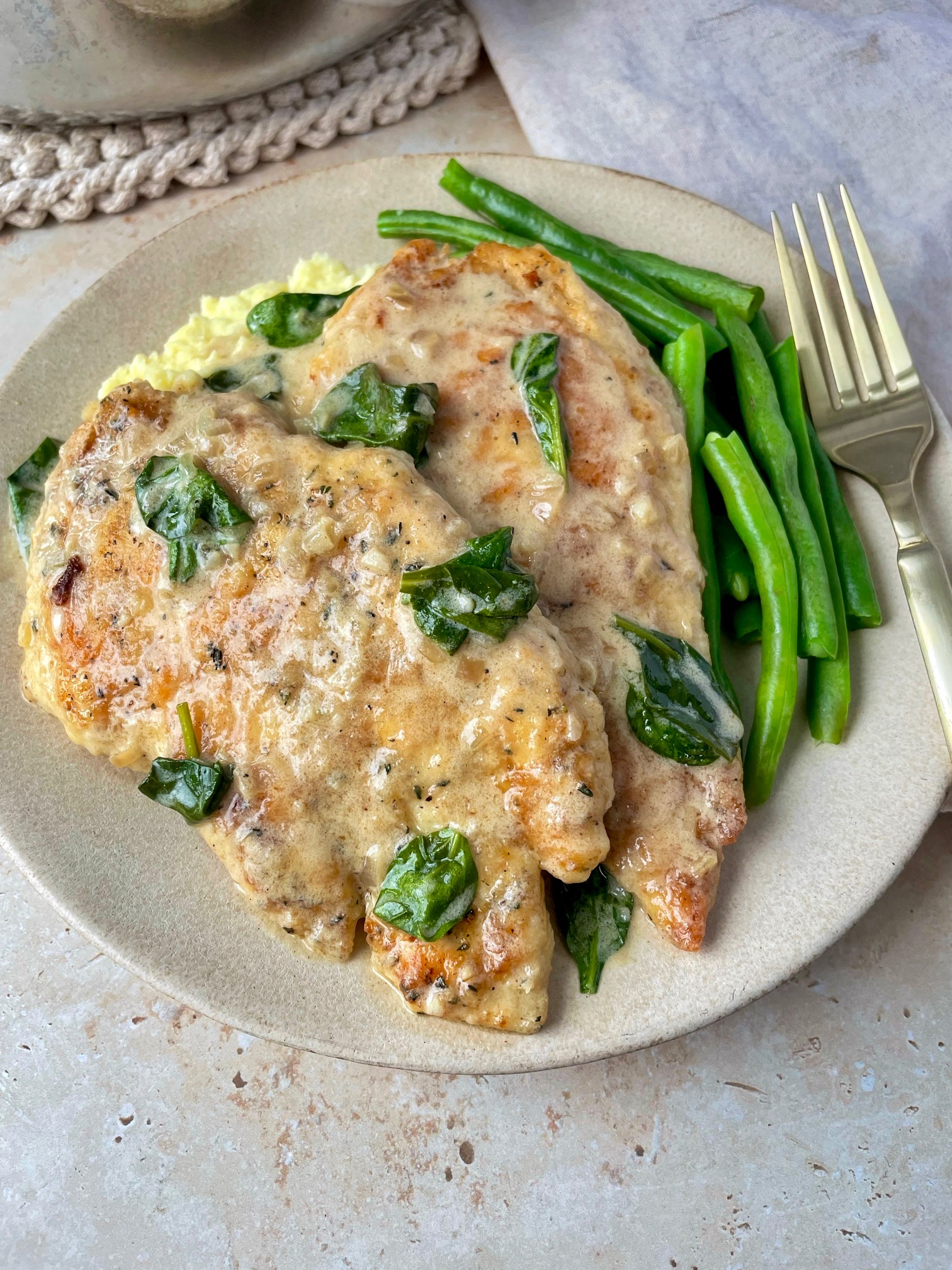 Dijon chicken on a bed of mashed potatoes and green beans.