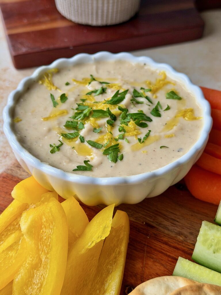 White bean dip topped with lemon zest and parsley served with dippers.