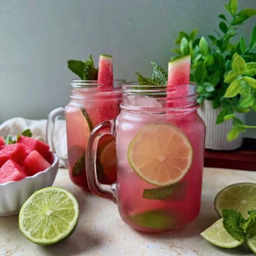 Two watermelon mojitos with garnishes.