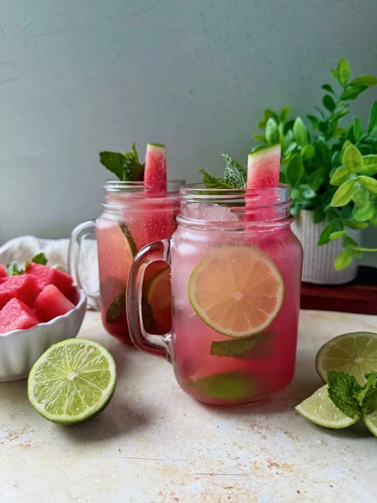 Two watermelon mojitos with garnishes.