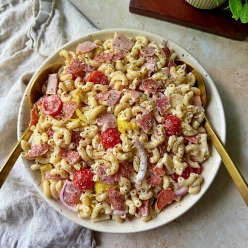 Italian Grinder Pasta Salad in a serving bowl with serving spoons and a napkin.
