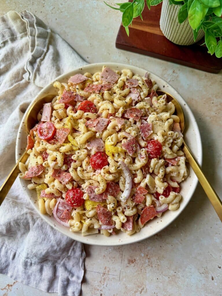 Italian Grinder Pasta Salad in a serving bowl with serving spoons and a napkin.