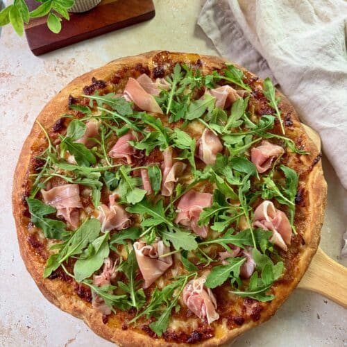 An overhead shot of fig prosciutto pizza on a pizza peel.