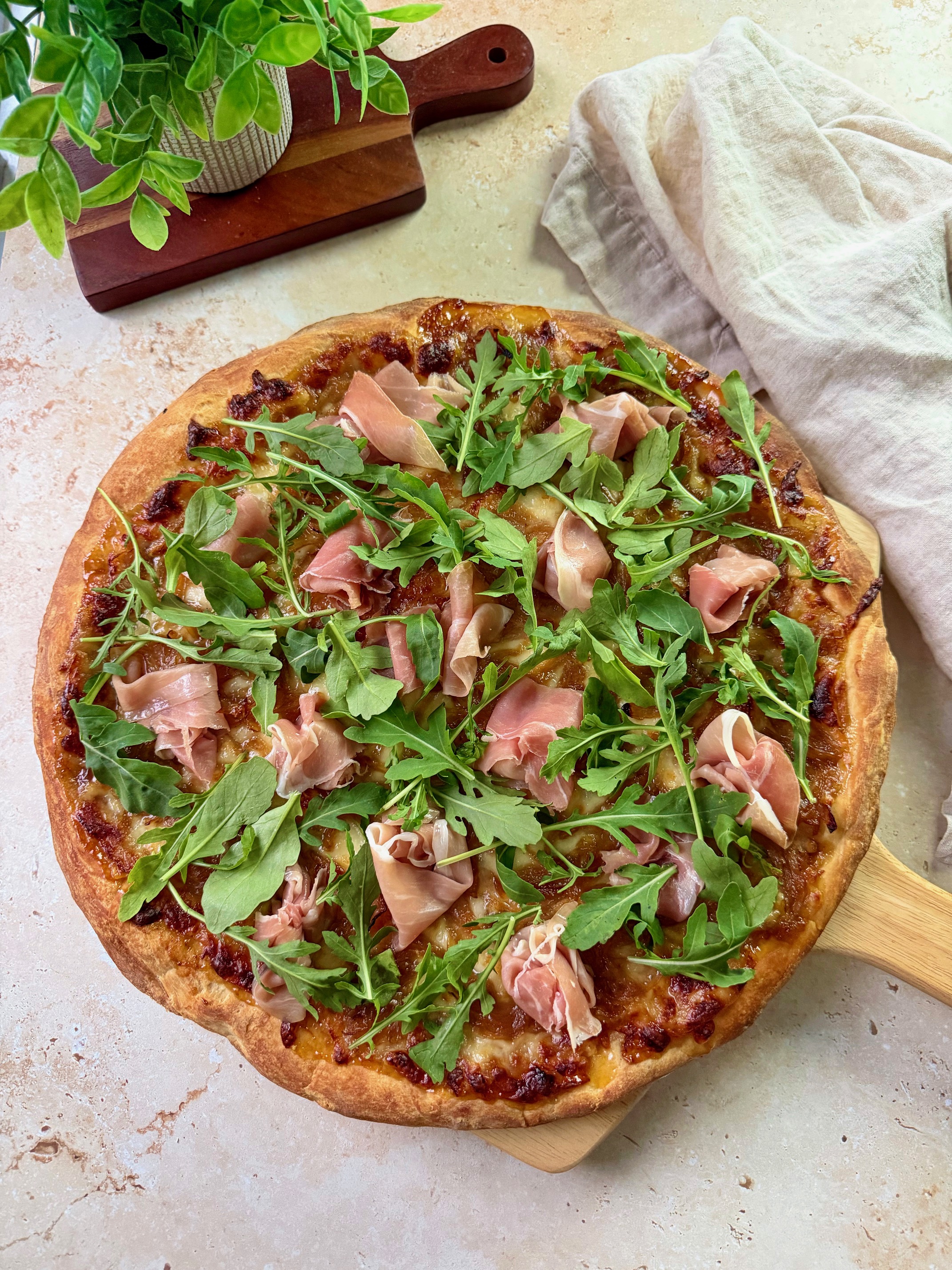 An overhead shot of a fig prosciutto pizza on a pizza peel.