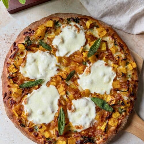 Butternut squash pizza topped with crispy sage on a pizza peel.