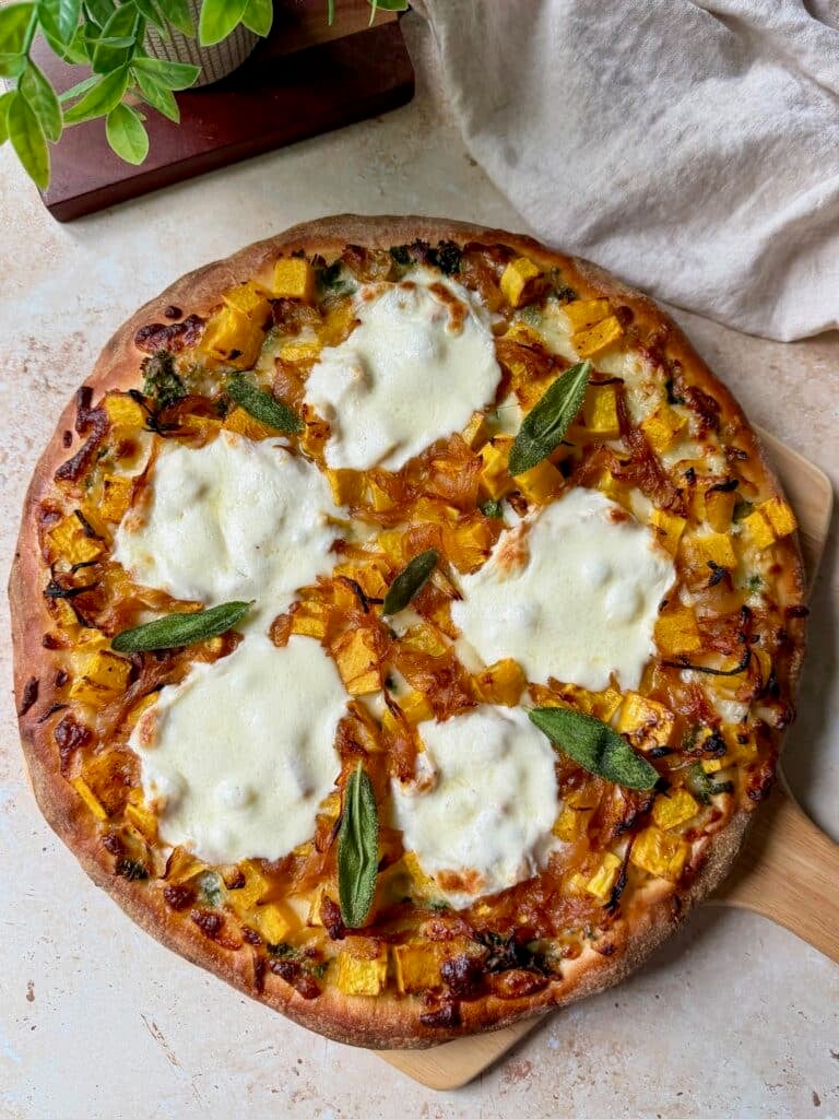 Butternut squash pizza topped with crispy sage on a pizza peel.